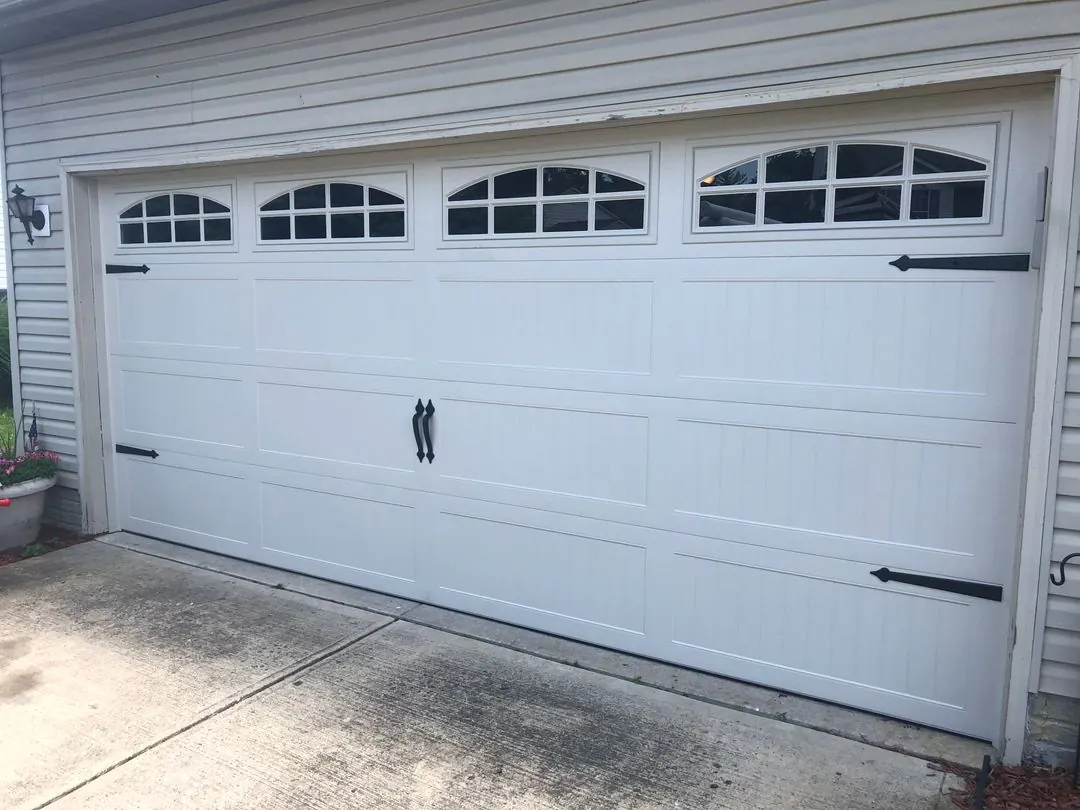 White carriage-style garage door with arched windows and black hardware