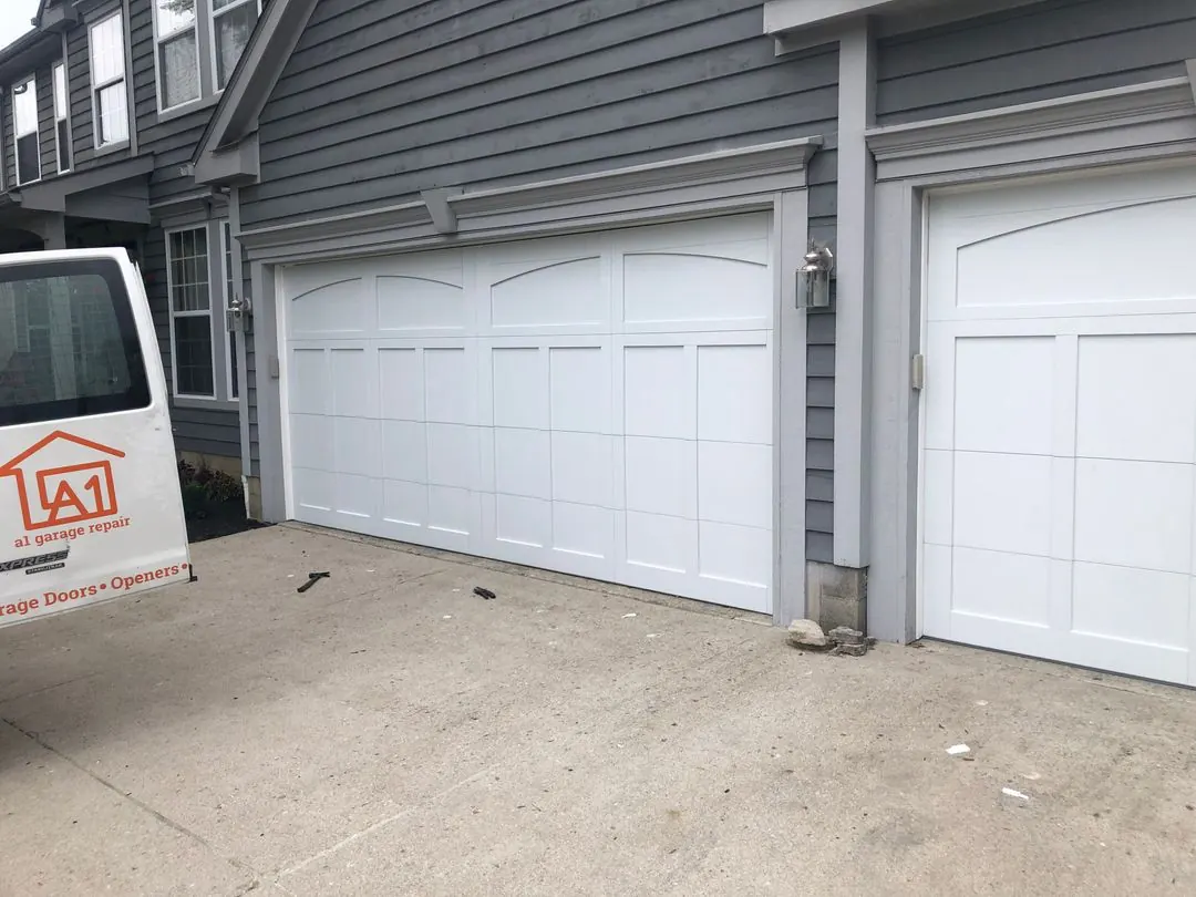 White carriage-style garage doors with the A1 Garage Repair van parked in front